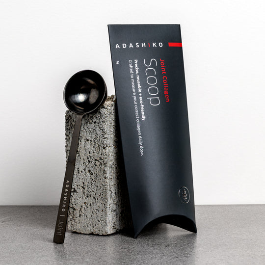 Adashiko Joint Collagen scoop and packaging on a gray surface with a white background | Adashiko Collagen | 100% Natural Skincare