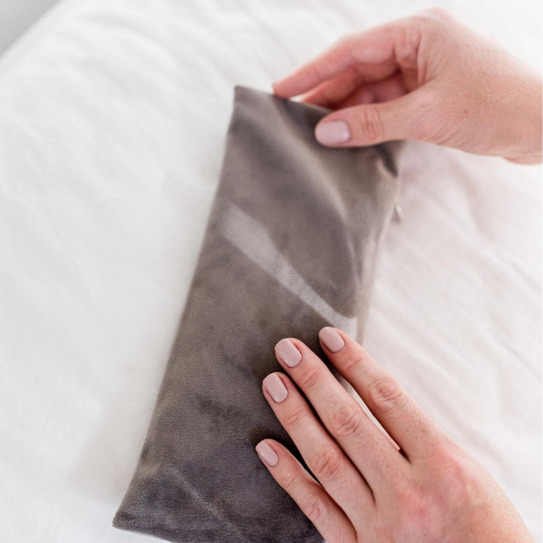 Plush Eye Pillow lying on a pillow being held by two hands | Adashiko Collagen | 100% Natural Skincare