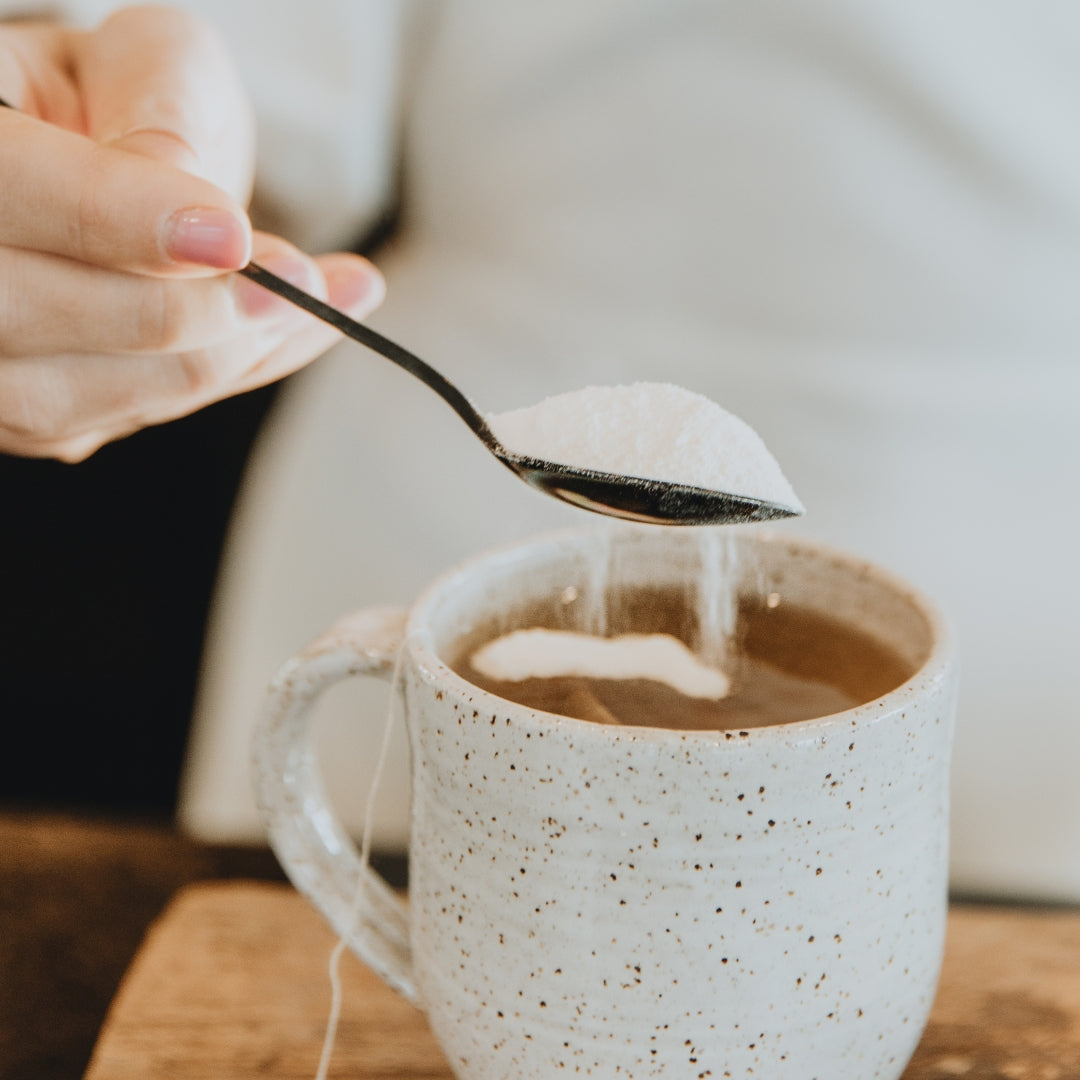Teaspoon of collagen powder being added to a mug of coffee | Adashiko Collagen | 100% Natural Skincare