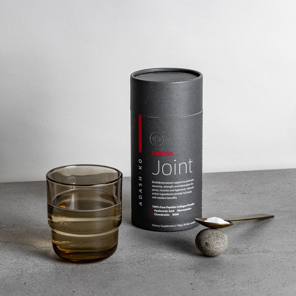 Tub of Joint Collagen Powder next to a glass of water and a spoon with powder against a grey background | Adashiko Collagen | 100% Natural Skincare